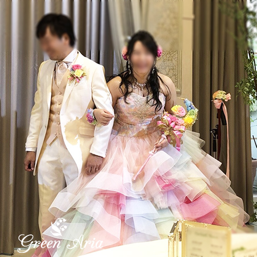 レインボーのドレスで、レインボー＆レインボーブーケを持つ新郎と腕を組んだ花嫁