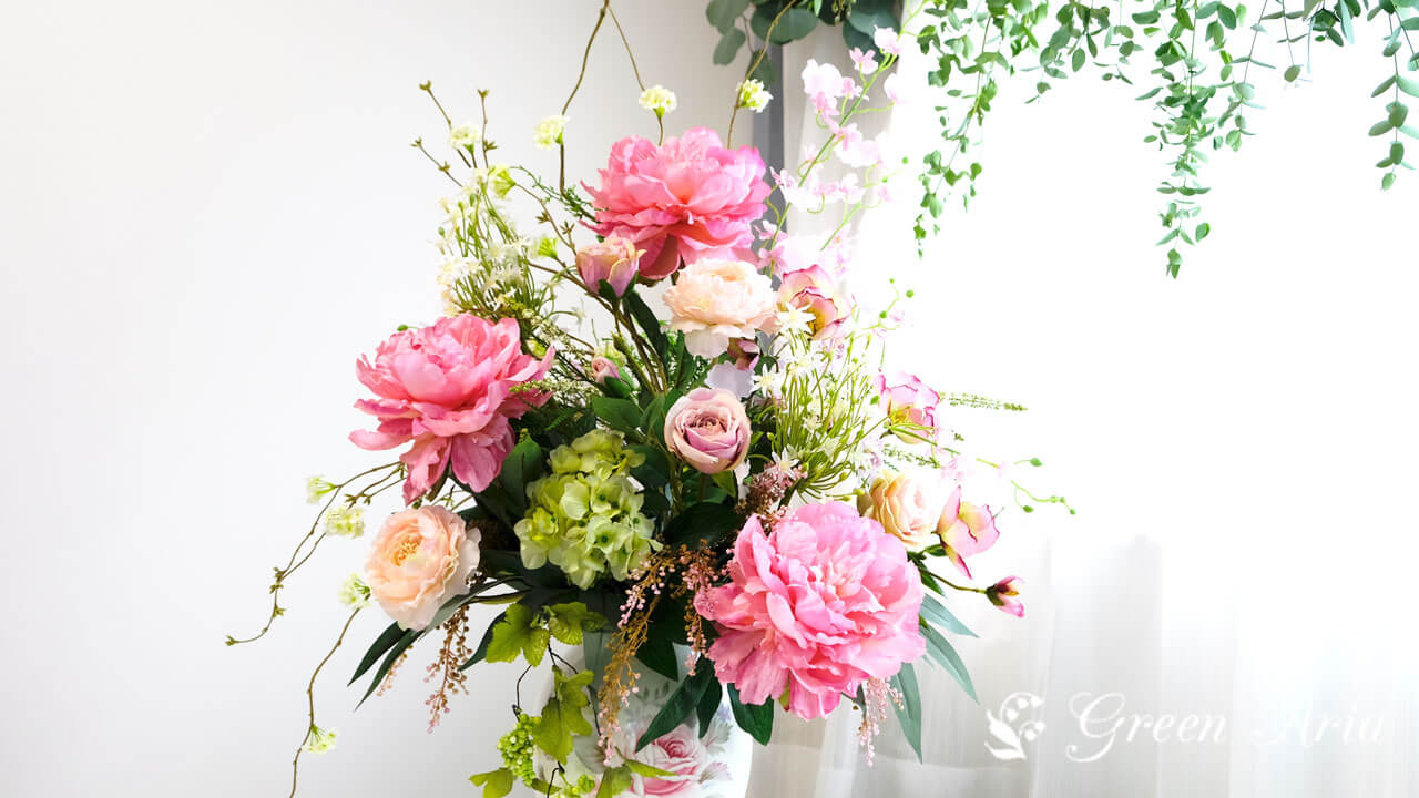 ピンクの芍薬とグリーンのあじさい、ピンクのバラやオレンジのラナンキュラスが美しいフラワーアレンジメント。テーブルの上に置けば空間がぱっと明るくなる。